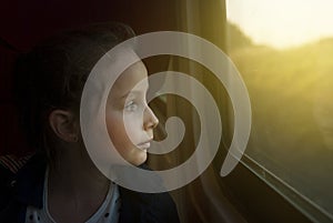 Vintage toned mage of Little Girl looking through window. She travels on a railway train. Copy space.