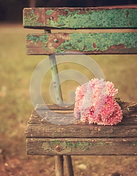 Vintage toned picture of pink flowers bouquet on a wooden old bench