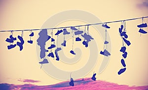 Vintage toned silhouettes of shoes hanging on cable.