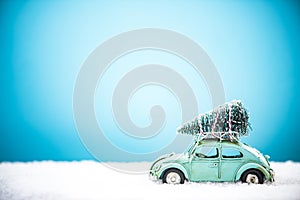 Vintage toy car carry Christmas tree in snow