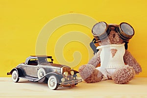 vintage toy car and cute teddy bear on wooden table