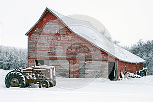 Vintage tractors in front of an old red barn in snow