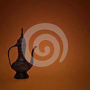 Vintage traditional islamic oriental engraved pitcher handmade on dark orange background. Elegant arabian antique tall metal jug photo