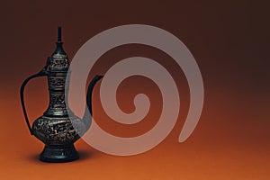 Vintage traditional islamic oriental engraved pitcher handmade on dark orange background. Elegant arabian tall metal jug photo