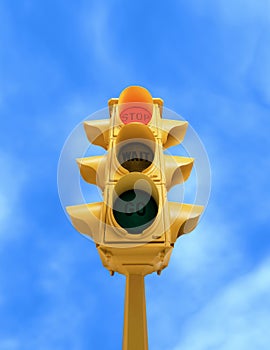 Vintage traffic light with red STOP light on blue sky background