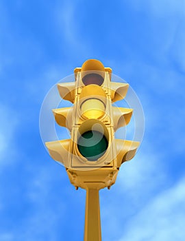 Vintage traffic light with yellow light on blue sky background