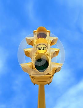 Vintage traffic light with yellow WAIT light on blue sky background