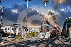 Vintage tram moving by building and palm trees at Santa Cruz Beach Boardwalk