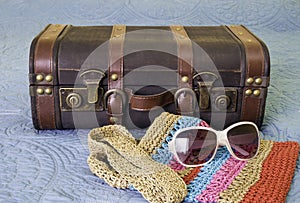 Vintage travel bag, suitcase and sunglasses on blue bed, travel