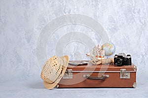 Vintage travel bag with summer marine accessories: retro camera, toy sailboat, straw hat, passport with money. Travel or tourism,