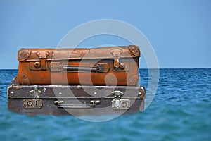 Vintage travel suitcases flaot in blue sea water