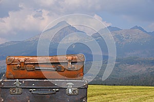 Vintage travel suitcases over mountain landscape