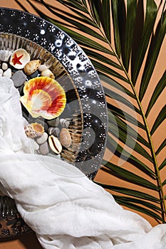 Vintage tray, gauze, sea shells, green palm leaf on nude beige background. Summer trendy boho flatly