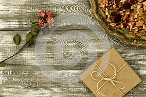 Vintage tray with petals of dried rose flowers, gift box wrapped in kraft paper on a gray table. Flat styling. Copy space for text