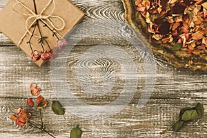 Vintage tray with petals of dried rose flowers, gift box wrapped in kraft paper on a gray table. Flat styling. Copy space for text