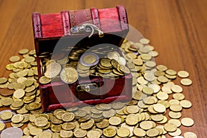 Vintage treasure chest full of golden coins on wooden background