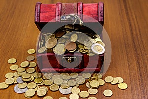 Vintage treasure chest full of golden coins on wooden background