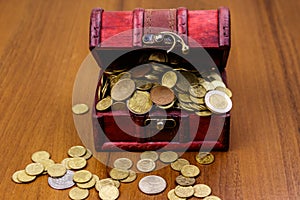 Vintage treasure chest full of golden coins on wooden background