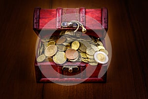 Vintage treasure chest full of golden coins on wooden background