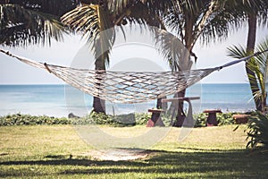 Vintage tropical background with hammock between palms on tropical beach and sea view
