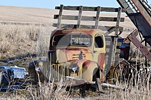 Vintage truck sits in a field with other old items.