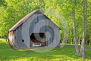 Vintage truck sits inside an old wooden barn.