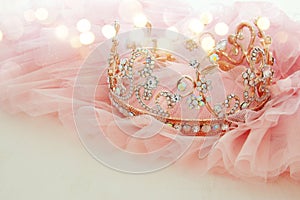 Vintage tulle pink chiffon dress and diamond tiara on wooden white table. Wedding and girl& x27;s party concept