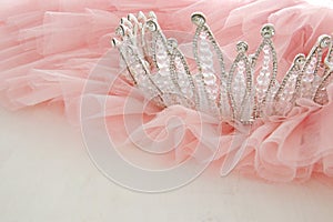 Vintage tulle pink chiffon dress and diamond tiara on wooden white table. Wedding and girl& x27;s party concept