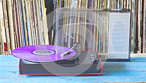 Vintage turntable with purple vinyl record and record collection