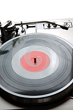 Turntable in silver case with vinyl record with red label isolated on white background. top