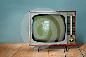 Vintage TV set on wooden table against old blue wall