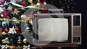 Vintage tv turned off next to Christmas tree with blinking lights