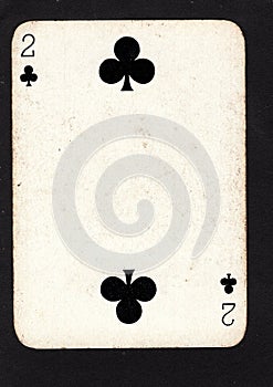 A vintage two of clubs playing card on a black background.