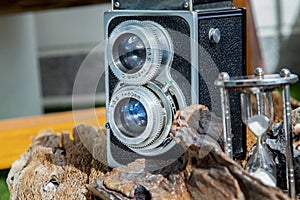 Vintage two lens photo camera with Hourglass on wooden background