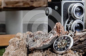 Vintage two lens photo camera with A retro pocket watch on wooden background