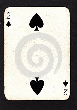 A vintage two of spades playing card on a black background.