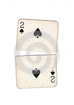 A vintage two of spades playing card torn in half.