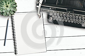 Vintage typewriter, blank notepad and pencil and succulent plant on rustic white wooden desk