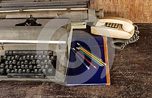 Vintage typewriter ,blue book, ,pencil and old telephone on ol