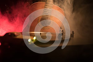 Vintage vinyl record playing on player and acoustic guitar on background with fire orange smoke. Blues concept. With Toy car