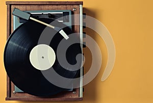 Vintage vinyl turntable with vinyl plate on a yellow pastel background. Entertainment 70s. Listen to music.