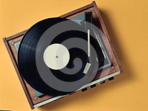 Vintage vinyl turntable with vinyl plate on a yellow pastel background. Listen to music. Top view.
