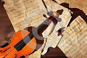 Vintage violin and old sheet music on wooden background closeup