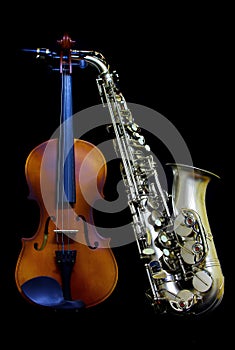 Vintage violin and silver matte finished alto saxophone on black background