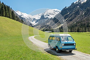 Vintage VW Bully camping car driving on mountain valley road