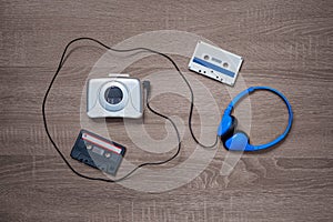 Vintage walkman, cassete and headphones on the wooden background.