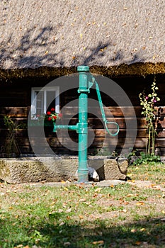 Vintage water pump on front of old wooden house