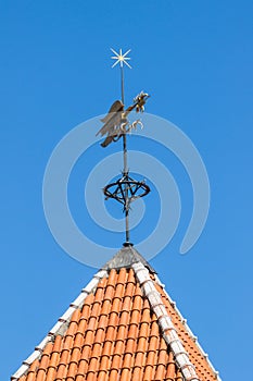 Vintage weather vane bird on the red roof a