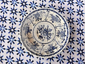 Vintage white and blue plate on blue tablecloth background