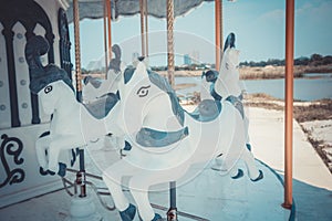 Vintage white carousel horse was abandoned in near urban area. It reminded the childhood happiness which children can play in
